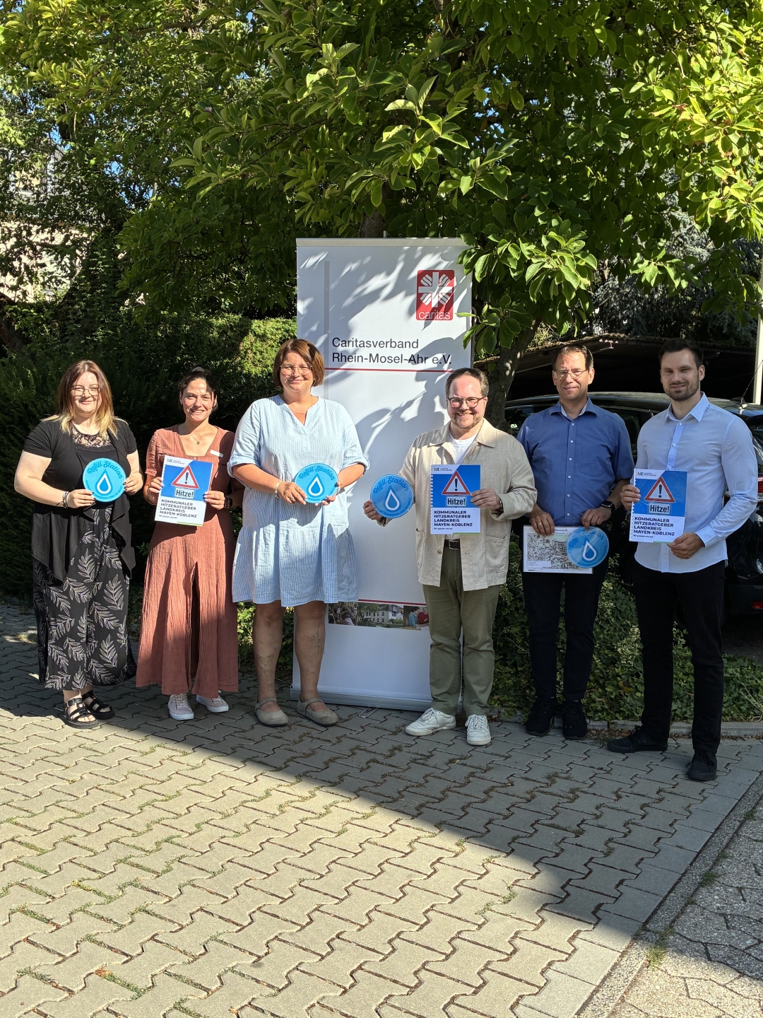 Christiane Böttcher, Bereichsleitung Soziale Dienste des Caritasverbands Rhein-Mosel-Ahr e. V. (3. v. l.) und der Erste Kreisbeigeordneter Pascal Badziong (4 v. l.), setzen sich gemeinsam mit der Stadt Andernach für mehr Hitzeschutz und Gesundheitsvorsorge im Landkreis Mayen-Koblenz ein. Christiane Böttcher, Bereichsleitung Soziale Dienste des Caritasverbands Rhein-Mosel-Ahr e. V. (3. v. l.) und der Erste Kreisbeigeordneter Pascal Badziong (4 v. l.), setzen sich gemeinsam mit der Stadt Andernach für mehr Hitzeschutz und Gesundheitsvorsorge im Landkreis Mayen-Koblenz ein.